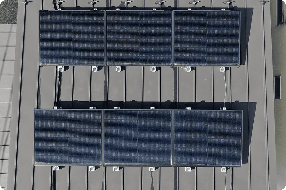 折板屋根に低めの架台で設置された太陽光パネルが整然と並ぶ