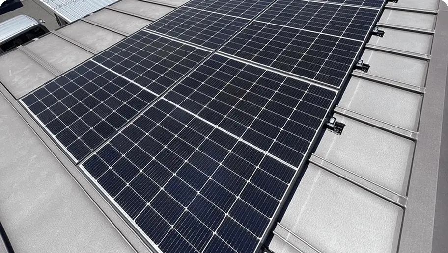 金属製のフラットな屋根に広く設置された太陽光パネルの全体写真