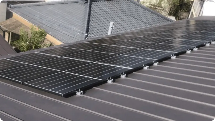 折板屋根に低めの架台で設置された太陽光パネルが整然と並ぶ