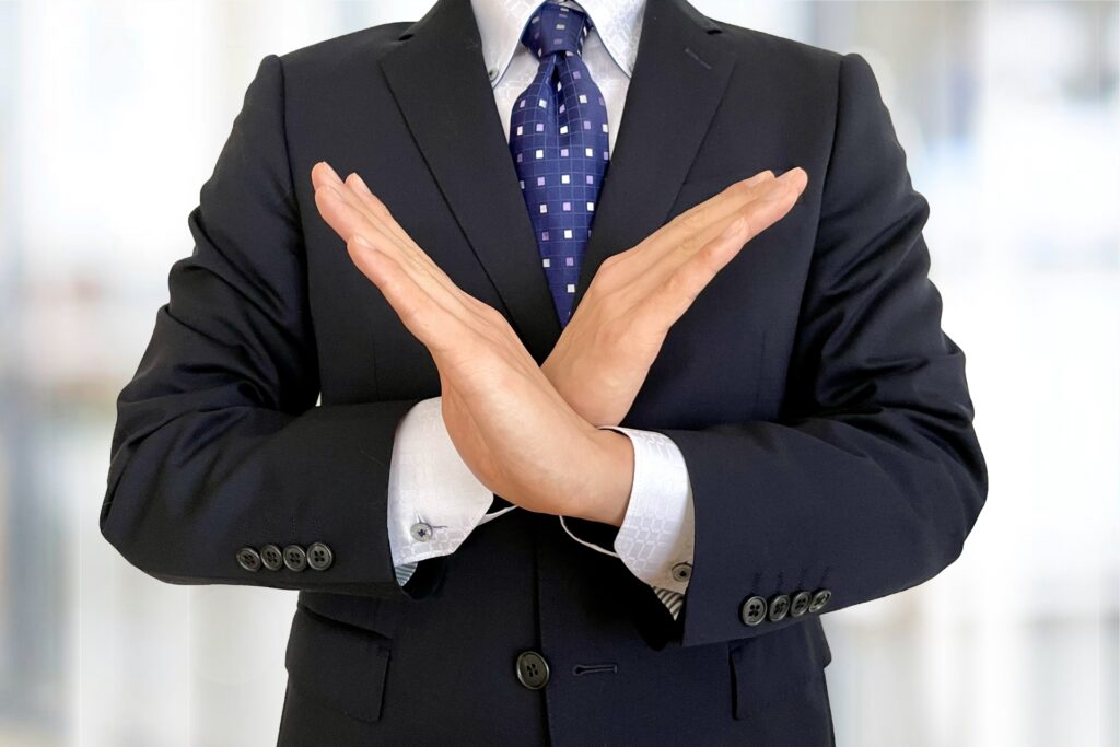 バツとしているスーツの男性